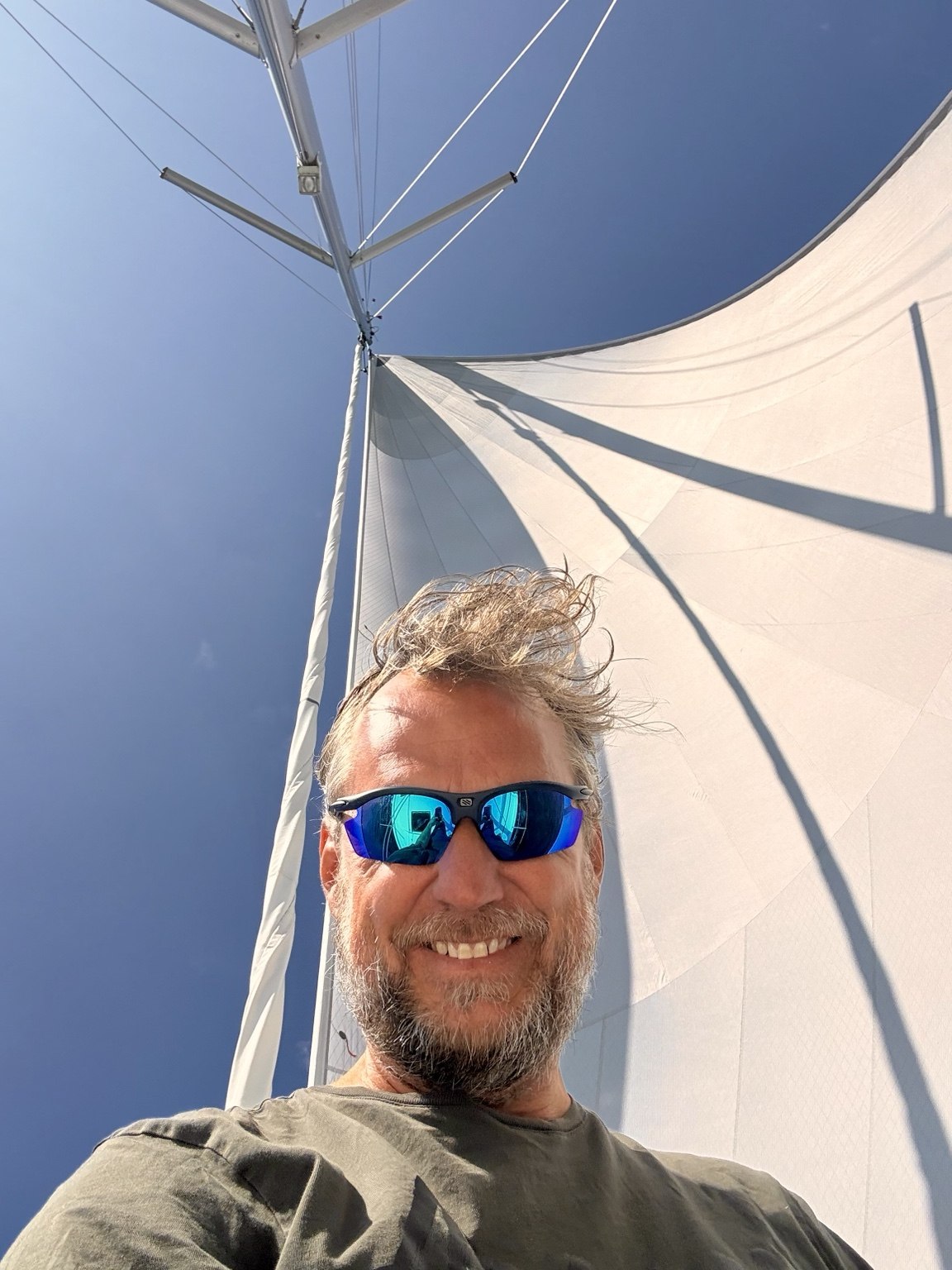 A portrait beneath a white sail and blue sky