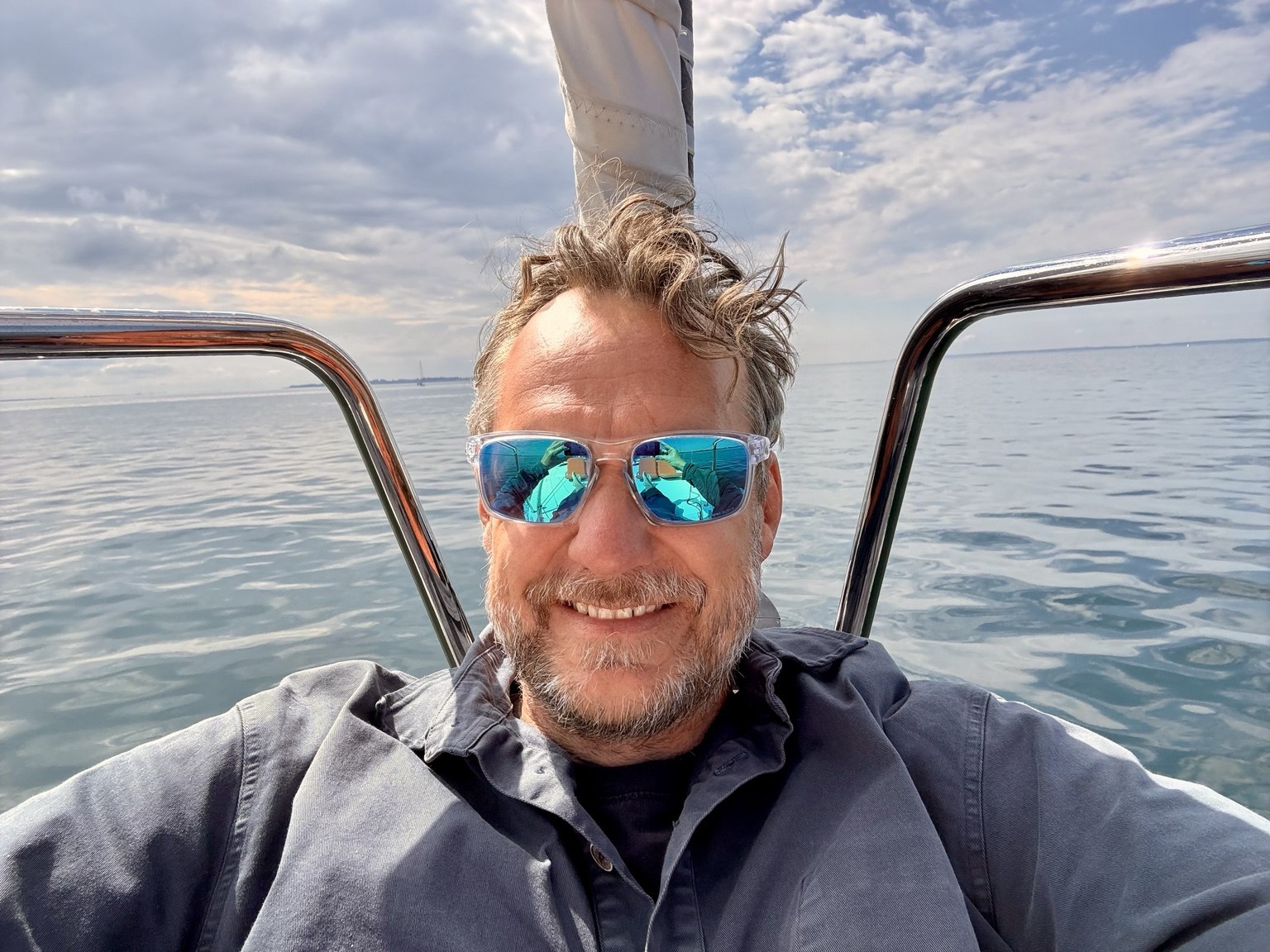 Portrait on a sailboat, wearing blue mirrored sunglasses